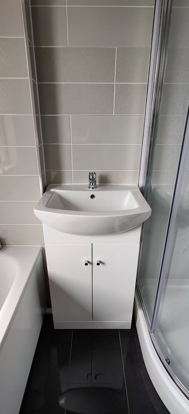 White basin vanity fitted between a bath and shower enclosure